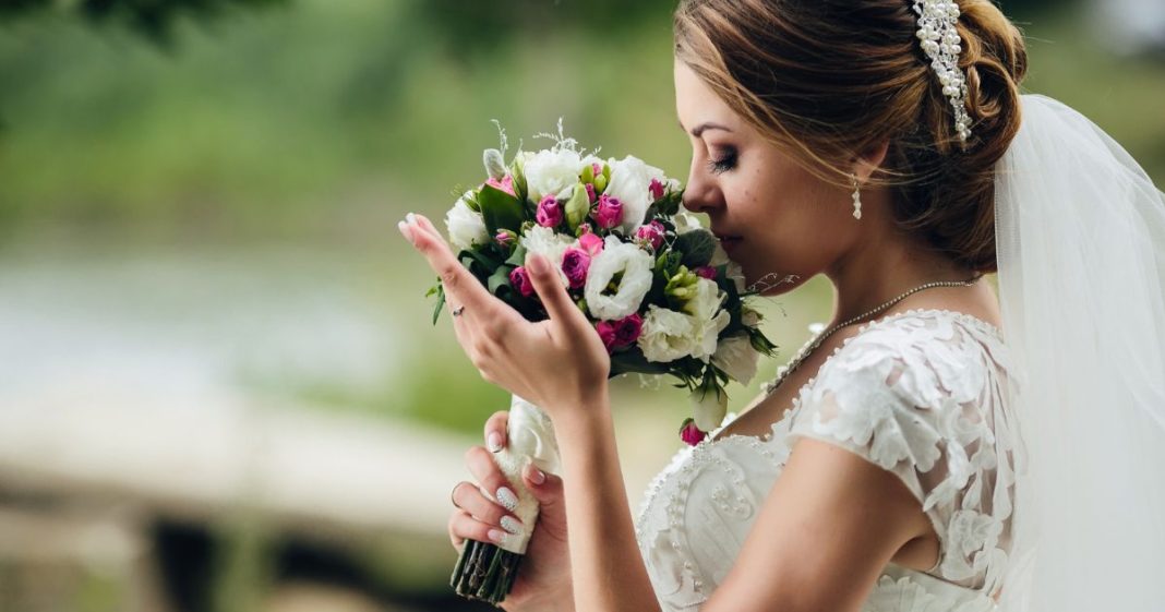 Noiva vestida para casamento cheirando um buquê de flores
