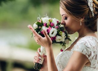 Noiva vestida para casamento cheirando um buquê de flores